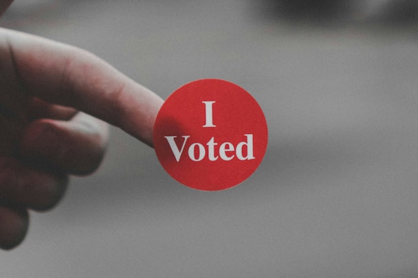 A sticker reading 'I voted' on the end of someone's finger A sticker reading 'I voted' on the end of someone's finger
